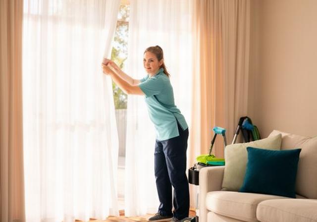 Cleaning team member opening bright curtains in a tidy Whyalla Norrie home